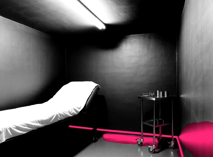 An empty clinic treatment room with a steel instrument trolley