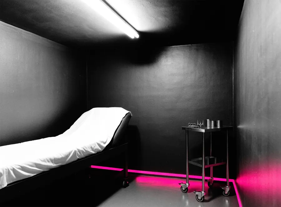 An empty clinic treatment room with a steel instrument trolley