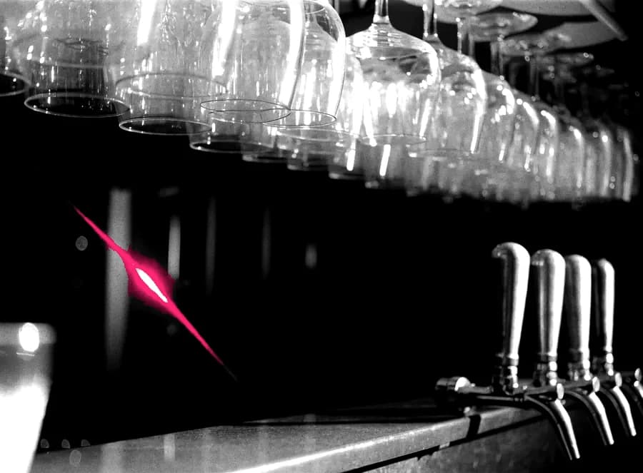 A dark bar counter with glassware and beer taps
