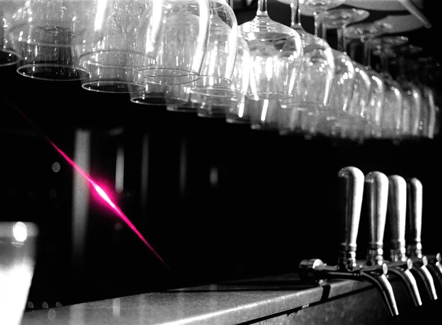 A dark bar counter with glassware and beer taps
