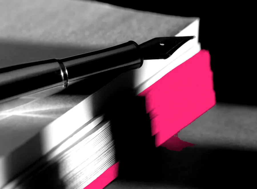 A stack of bound documents and a fountain pen, lit from the side