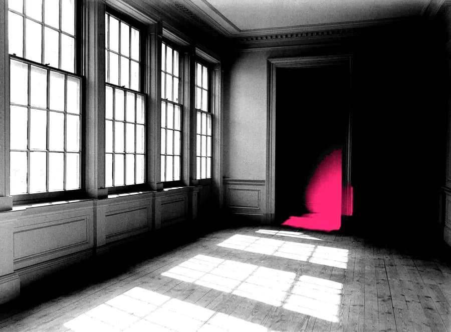 An empty period room with tall windows and bare floorboards