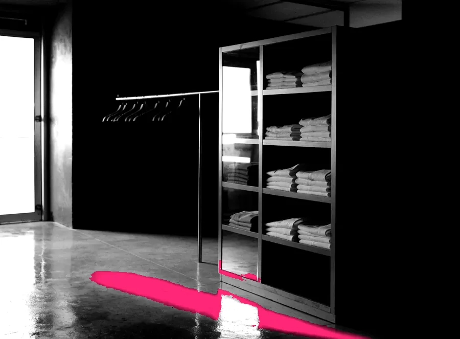 An empty boutique interior at night with a single clothing rail