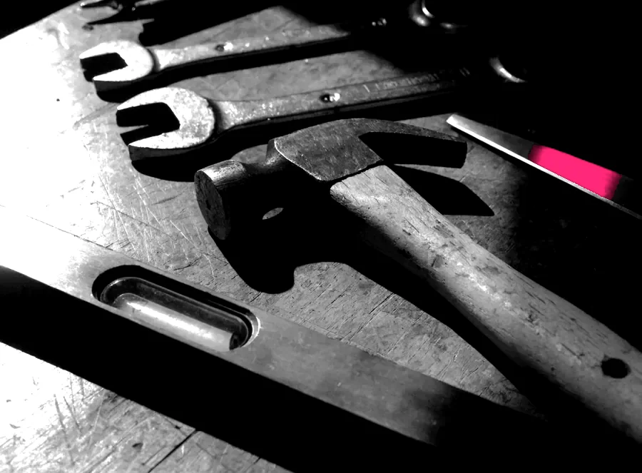 Well-used hand tools laid out on a dark workbench