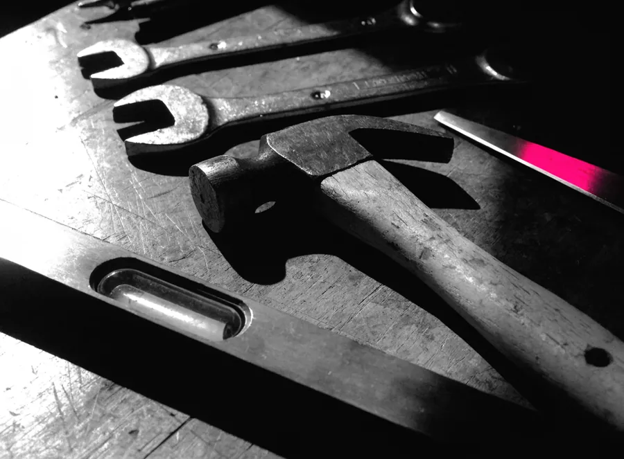 Well-used hand tools laid out on a dark workbench